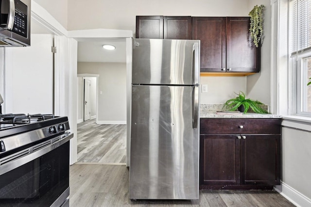 kitchen with dark brown cabinets, light wood-style flooring, and appliances with stainless steel finishes