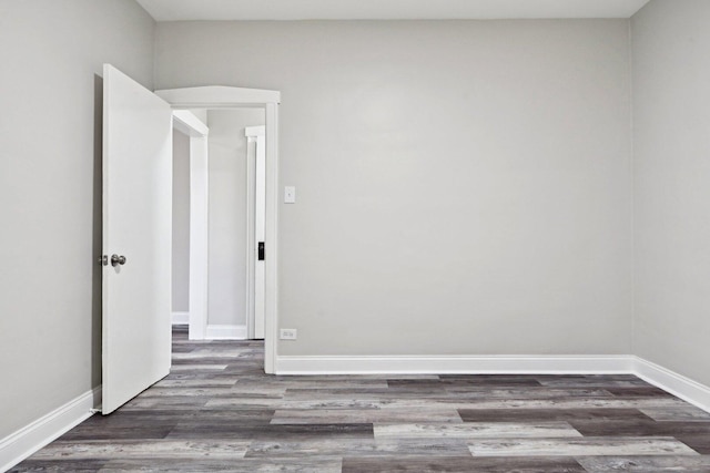 spare room featuring baseboards and dark wood-style flooring