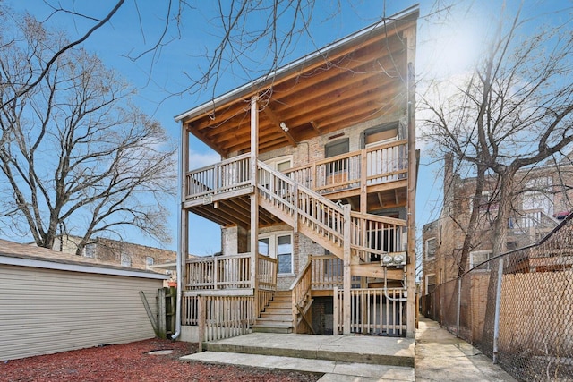 back of property with stairs, fence, and a wooden deck