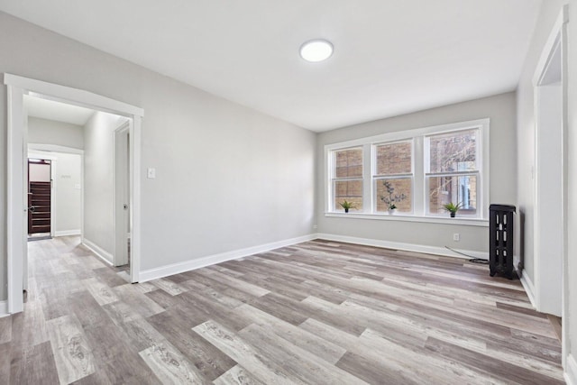 spare room with baseboards, wood finished floors, and stairs