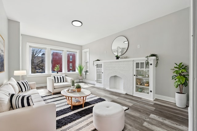 living area featuring a brick fireplace, wood finished floors, and baseboards