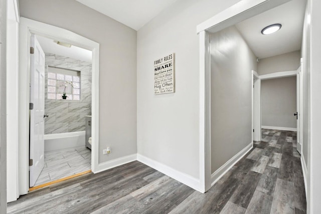 hallway featuring wood finished floors and baseboards