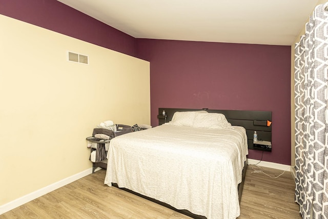 bedroom featuring visible vents, baseboards, and wood finished floors