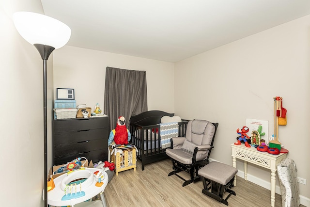 bedroom featuring a crib, baseboards, and wood finished floors