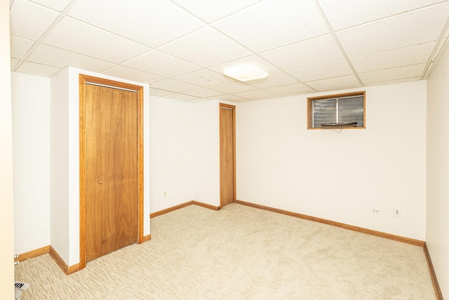 finished basement featuring baseboards, a drop ceiling, and light carpet