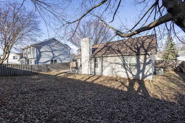 rear view of property featuring a chimney and fence private yard