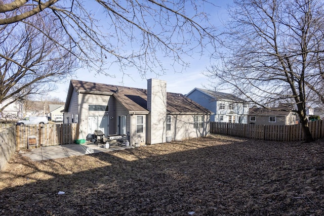 rear view of property with a patio, a fenced backyard, and a chimney