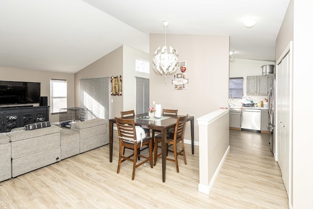 dining area featuring an inviting chandelier, light wood-type flooring, baseboards, and vaulted ceiling