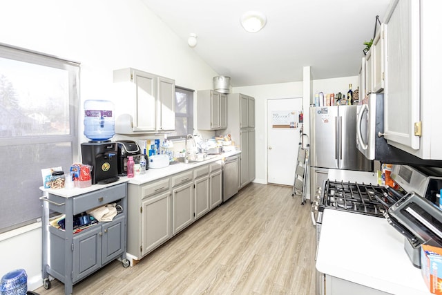 kitchen with stainless steel appliances, light countertops, gray cabinets, and vaulted ceiling