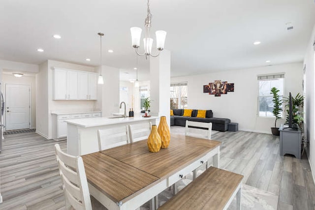 dining space featuring light wood-style flooring, a notable chandelier, recessed lighting, and baseboards