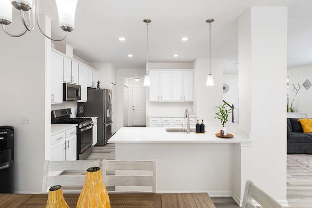 kitchen with white cabinetry, a peninsula, hanging light fixtures, and stainless steel appliances