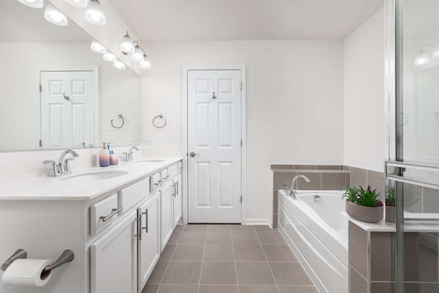 bathroom featuring tile patterned floors, a bath, double vanity, and a sink