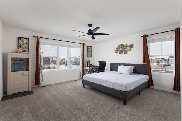 carpeted bedroom featuring baseboards, multiple windows, and ceiling fan