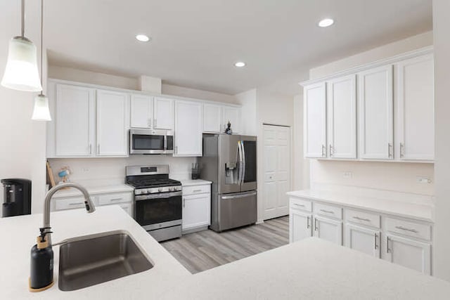 kitchen with white cabinets, appliances with stainless steel finishes, light countertops, and a sink