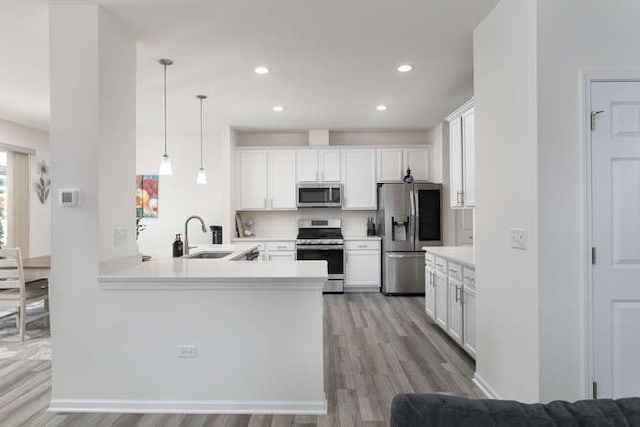 kitchen featuring a sink, stainless steel appliances, white cabinets, light wood finished floors, and light countertops