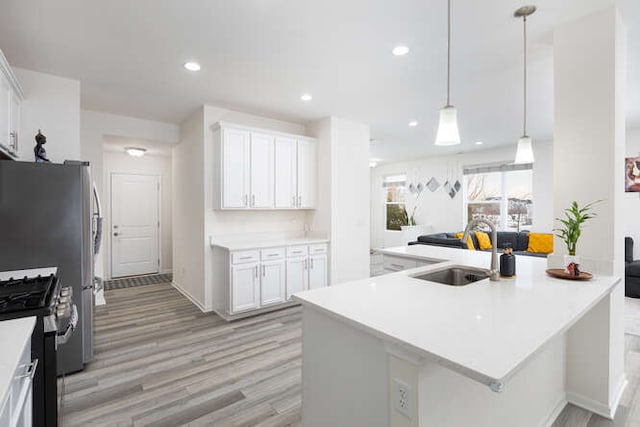 kitchen with recessed lighting, light wood-style floors, stainless steel range with gas cooktop, and a sink