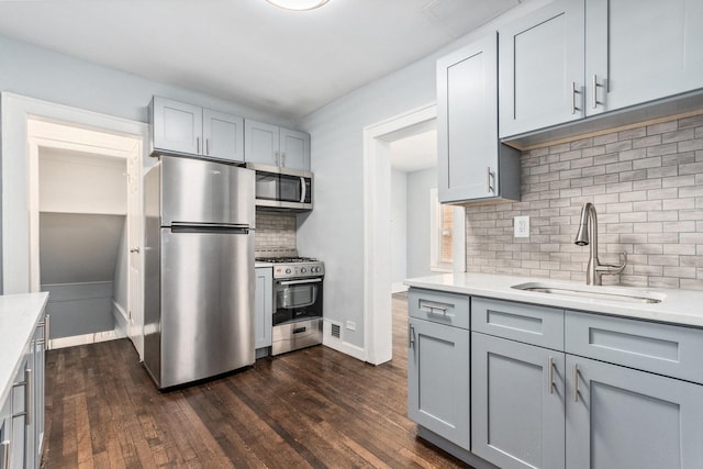 kitchen featuring dark wood-style floors, gray cabinets, appliances with stainless steel finishes, and a sink