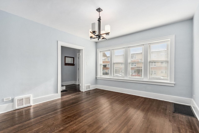 spare room with a notable chandelier, visible vents, baseboards, and dark wood-style flooring