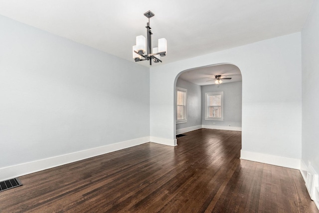 spare room with visible vents, arched walkways, dark wood-type flooring, and baseboards