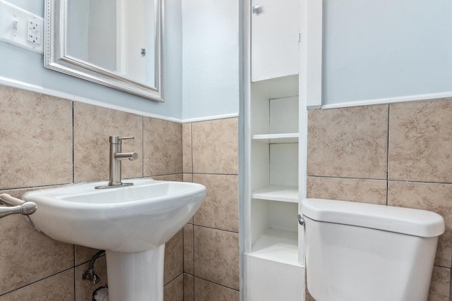 bathroom featuring wainscoting, tile walls, and toilet