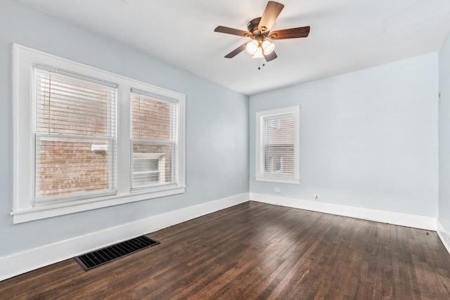 unfurnished room featuring baseboards, visible vents, dark wood-style flooring, and ceiling fan