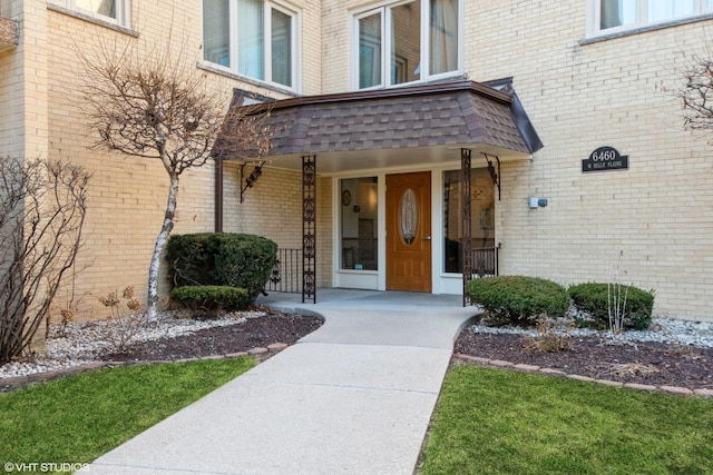 doorway to property featuring brick siding and covered porch