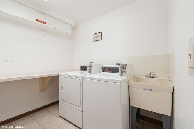 clothes washing area featuring light tile patterned floors, baseboards, a sink, and washing machine and clothes dryer