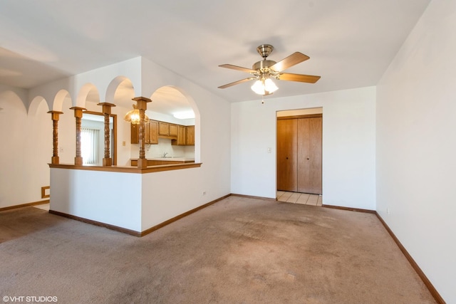 unfurnished living room with light colored carpet, baseboards, and ceiling fan