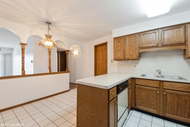kitchen with a sink, tasteful backsplash, arched walkways, a peninsula, and white dishwasher