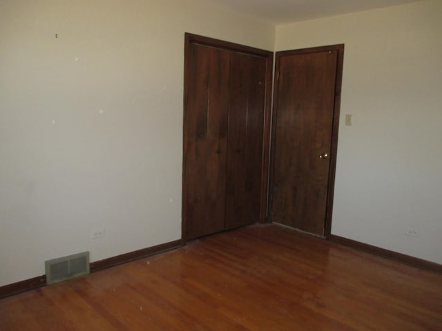 unfurnished bedroom with visible vents, baseboards, a closet, and wood finished floors