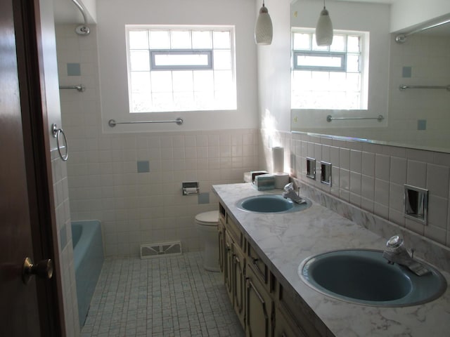 full bath with tile walls, toilet, visible vents, and a sink