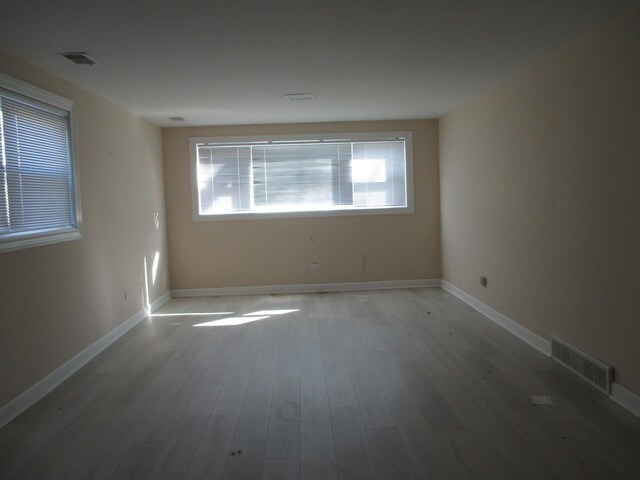 unfurnished room featuring wood finished floors, visible vents, and baseboards