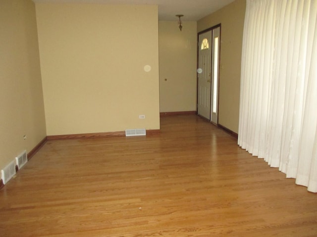 empty room featuring visible vents, baseboards, and light wood finished floors