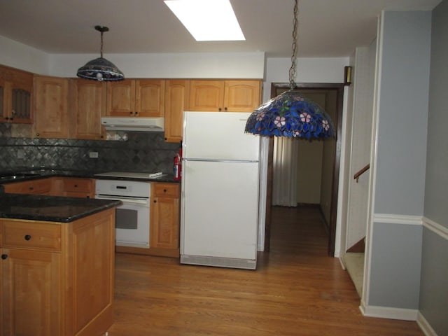 kitchen with backsplash, under cabinet range hood, light wood-type flooring, a skylight, and white appliances