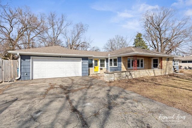 ranch-style home featuring aphalt driveway, a garage, roof with shingles, and fence