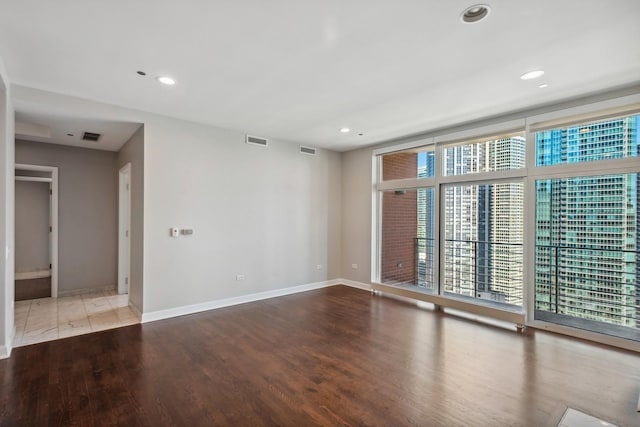 unfurnished room featuring visible vents, baseboards, and wood finished floors