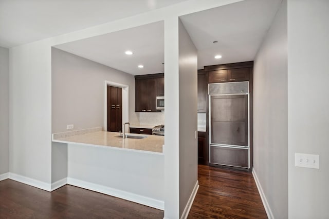 kitchen featuring a sink, dark brown cabinets, dark wood finished floors, and stainless steel appliances