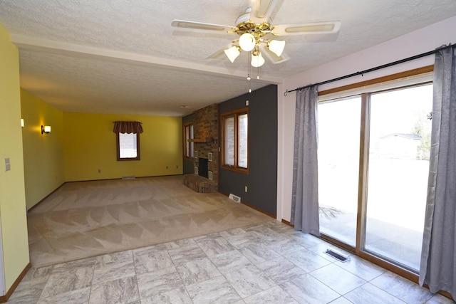 unfurnished living room with visible vents, a ceiling fan, a textured ceiling, carpet floors, and a brick fireplace