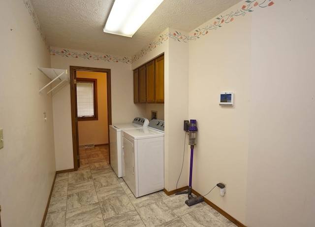 clothes washing area with baseboards, cabinet space, a textured ceiling, and independent washer and dryer