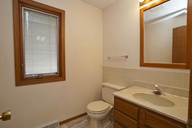 bathroom featuring vanity, baseboards, a textured ceiling, tile patterned floors, and toilet