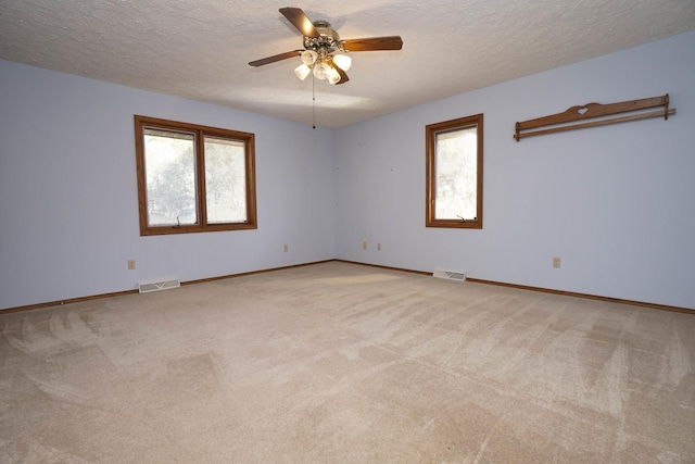 unfurnished room with visible vents, light colored carpet, ceiling fan, and a textured ceiling