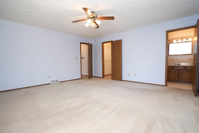 unfurnished bedroom with baseboards, light colored carpet, visible vents, and a textured ceiling