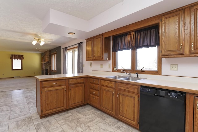 kitchen featuring dishwasher, light countertops, brown cabinets, a peninsula, and a sink