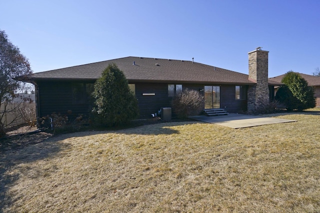 back of property with a lawn, entry steps, a patio, central AC unit, and a chimney