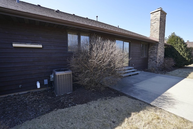 view of side of home featuring central air condition unit, a patio area, and a chimney