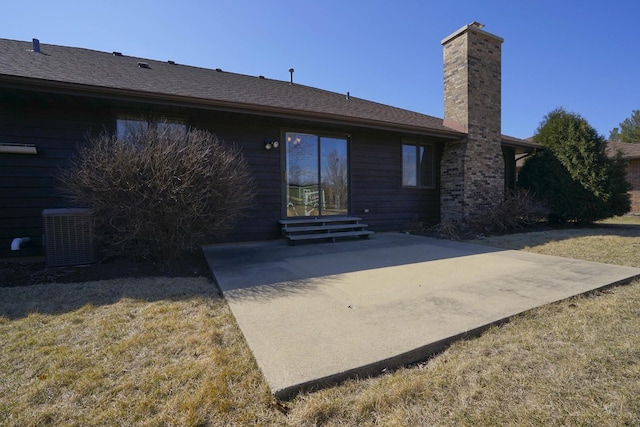 back of property with entry steps, central AC, a chimney, and a patio area