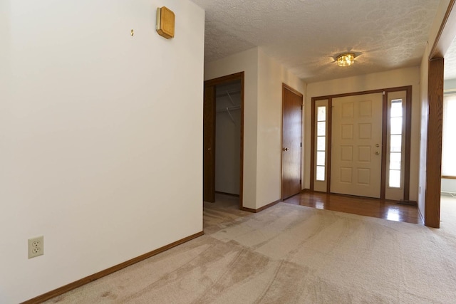 entryway featuring baseboards, carpet floors, and a textured ceiling