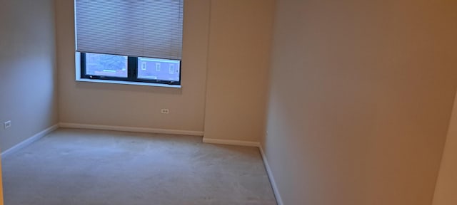 unfurnished room with baseboards and light carpet