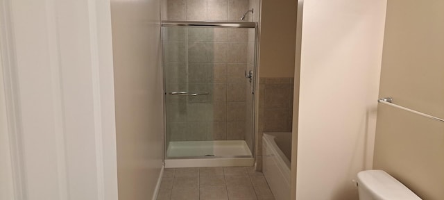 full bath with tile patterned flooring, toilet, and a tile shower