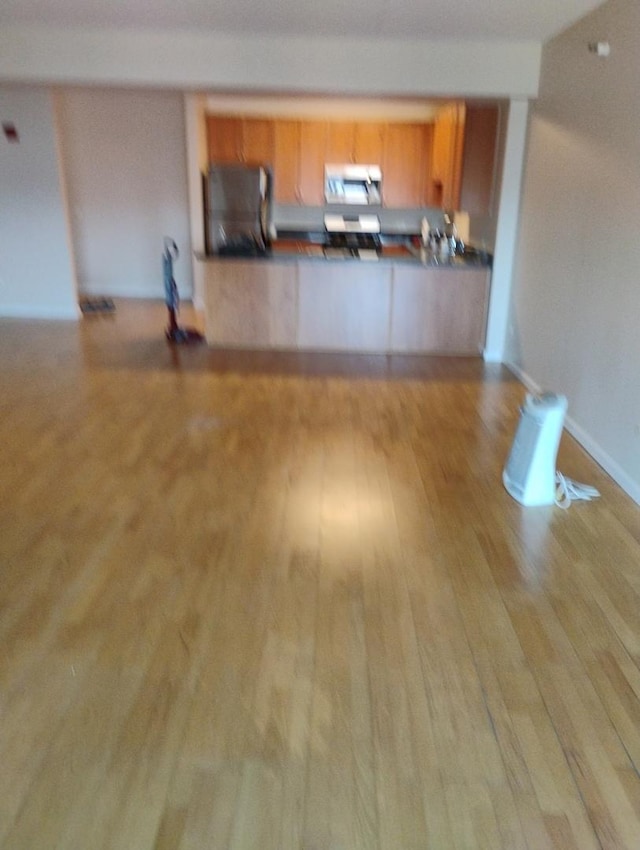 unfurnished living room featuring baseboards and wood finished floors